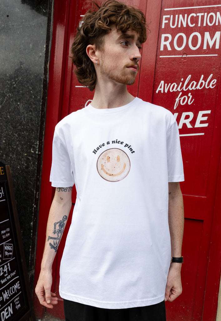 male model wears unisex white t shirt with "have a nice pint" slogan and smiley beer graphic