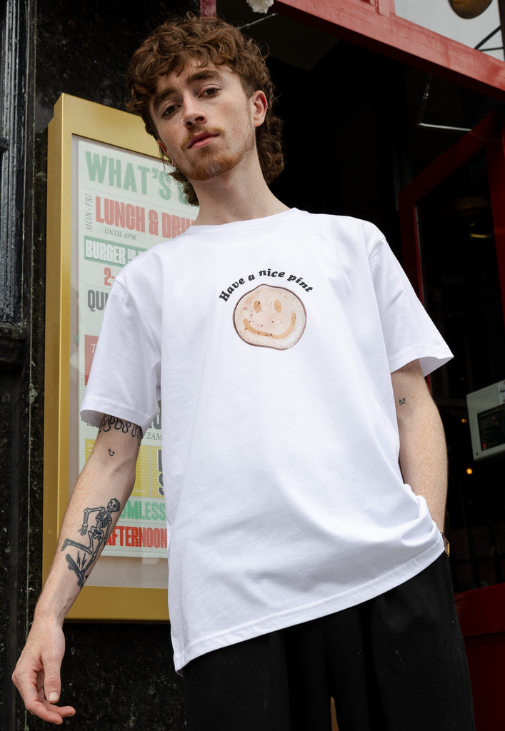 male model wears casual white printed t shirt with have a nice pint slogan and smiley beer logo