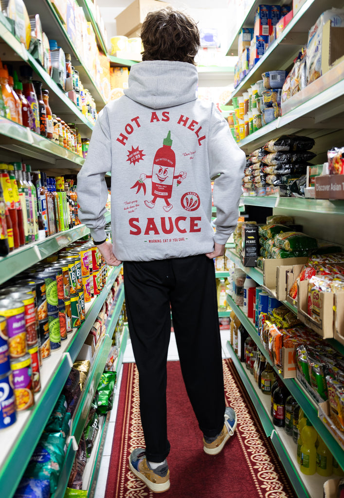 male model wears grey hoodie with large hot sauce graphic print to back