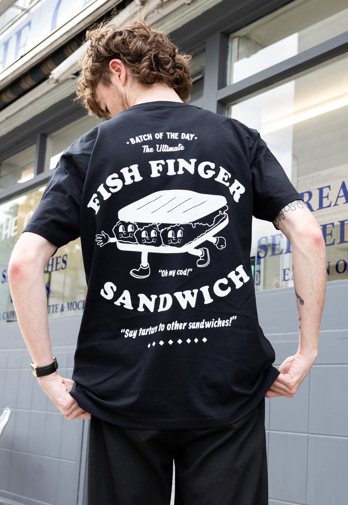 Model wears large back printed  black tshirt of fish finger sandwich graphic print in white