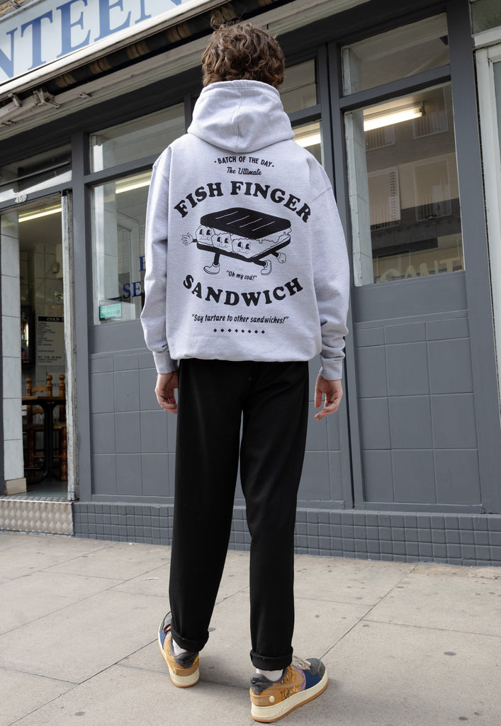 Lifestyle images of model wearing large back fish finger sandwich logo printed hoodie in grey