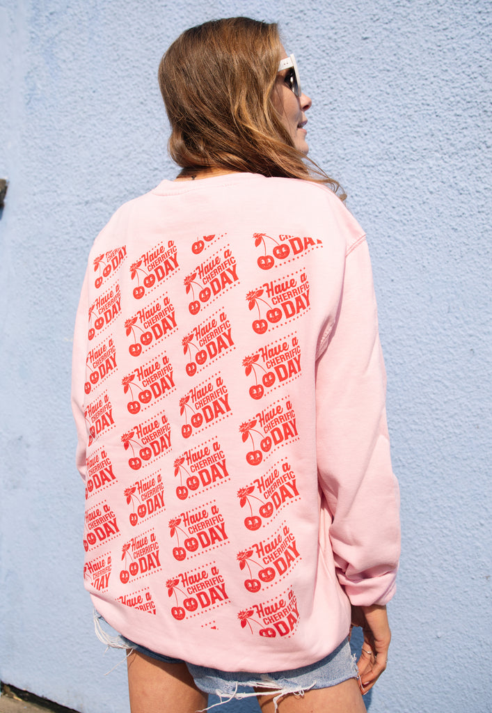 female model is wearing casual pink sweatshirt with repeat pattern cherry logo back print