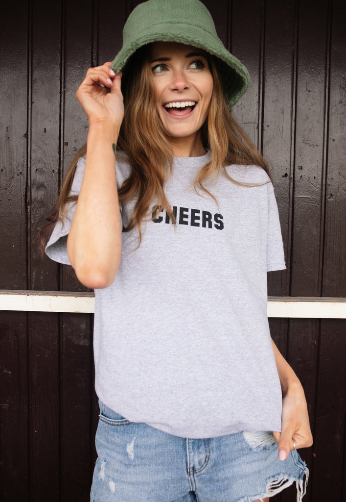 Model wears grey tshirt with Cheers slogan