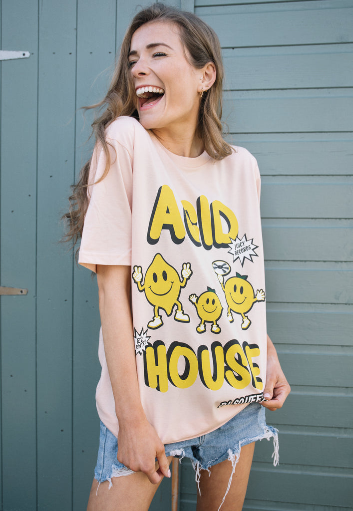 model is wearing organic, relaxed fit peach coloured festival t-shirt with "acid house" slogan and citrus fruit graphics