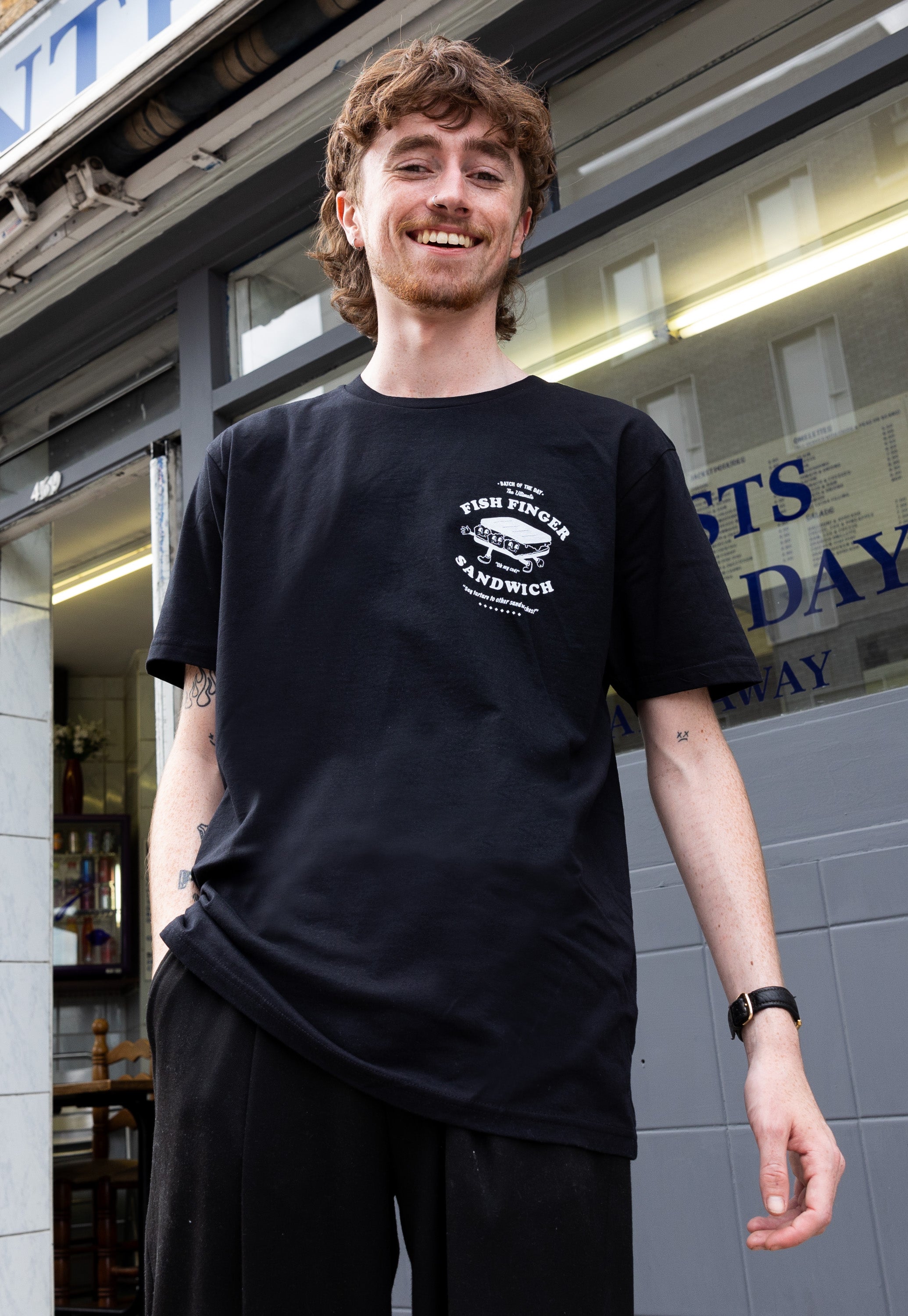 Model wears small front logo of fish finger sandwich in black tshirt
