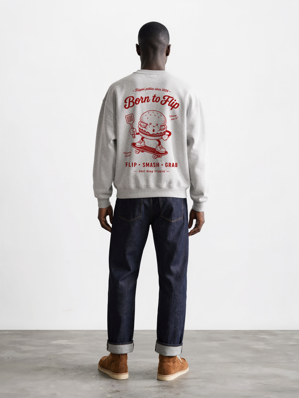 Male model wearing the Born to Flip ash grey oversized sweatshirt, back view with large deep red skateboarding burger artwork across the back.