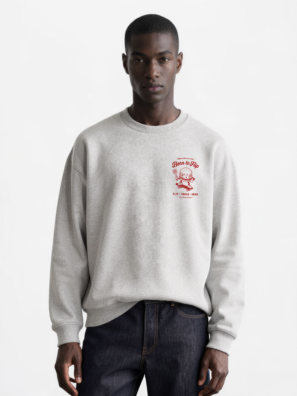 Male model wearing the Born to Flip ash grey oversized sweatshirt, front view with small deep red burger artwork on the left chest.