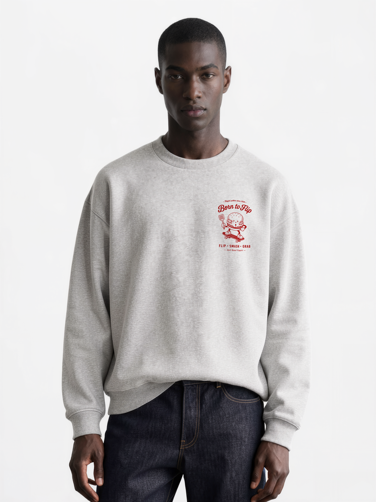 Male model wearing the Born to Flip ash grey oversized sweatshirt, front view with small deep red burger artwork on the left chest.