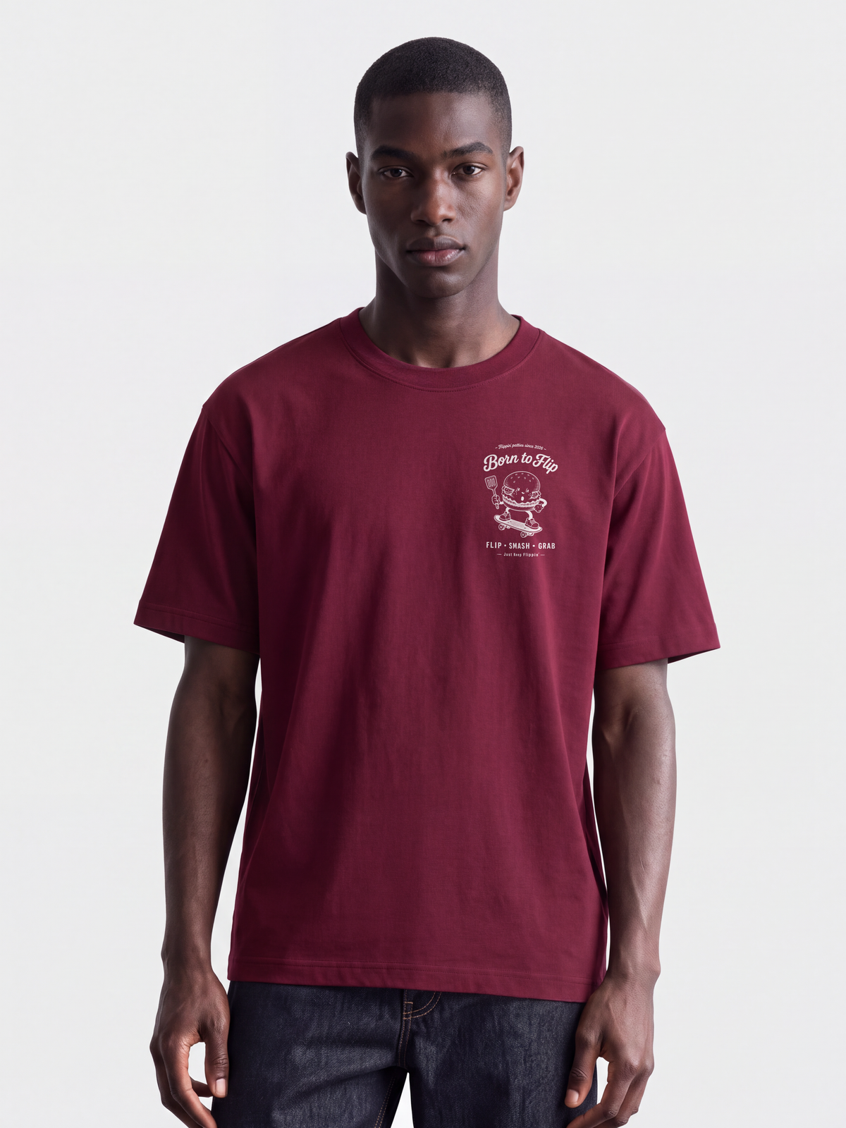 Male model wearing the Born to Flip burgundy T-shirt, front view with small white burger artwork on the left chest.