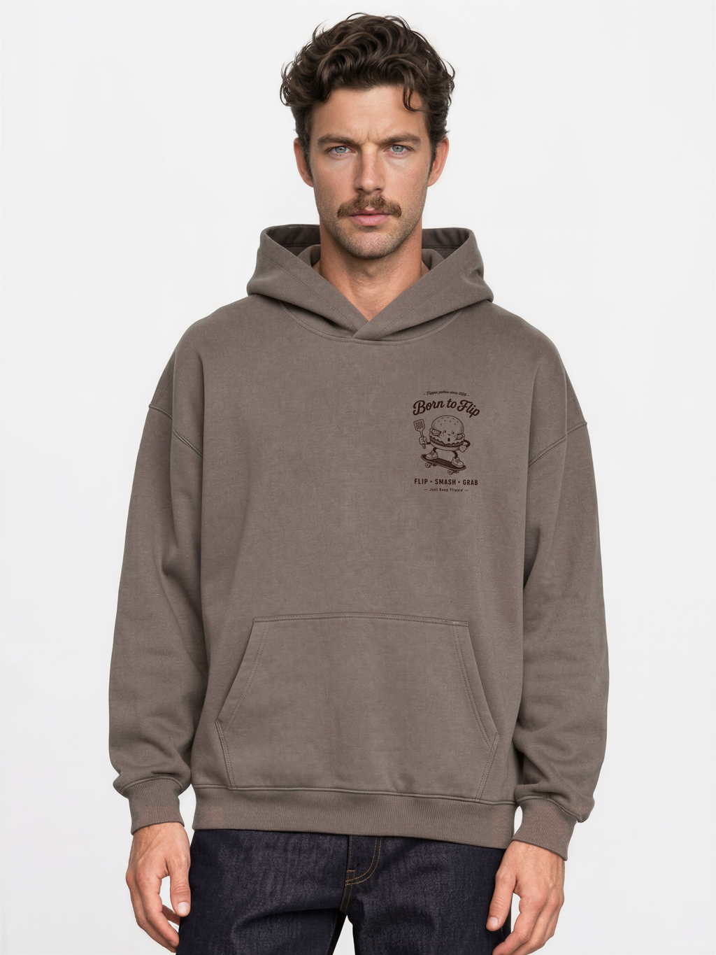 Male model wearing the Born to Flip taupe oversized hoodie, front view with small brown burger artwork on the left chest.