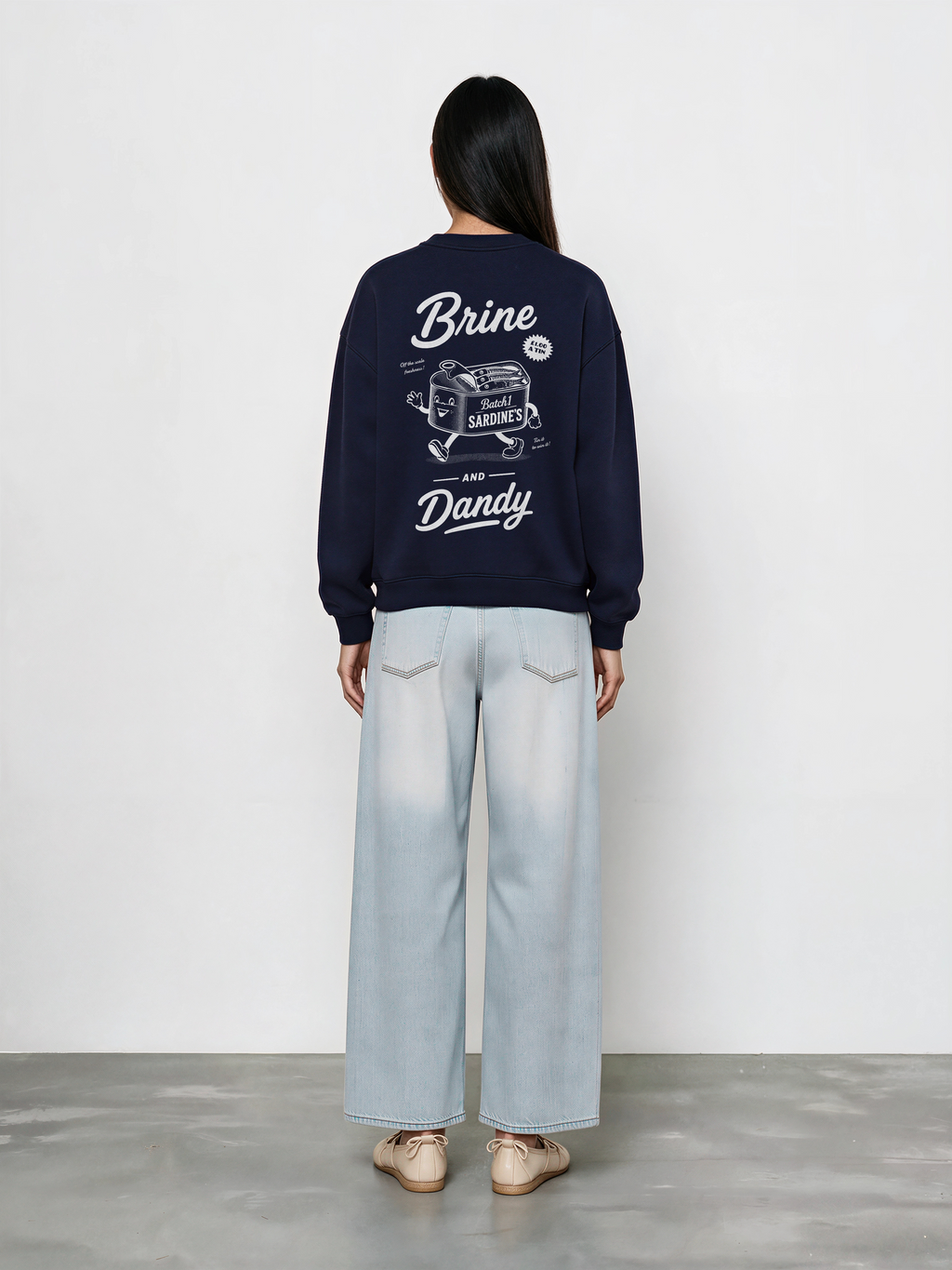 Brine and Dandy navy sweatshirt, back female model, showing the larger white Brine and Dandy sardine design on the back