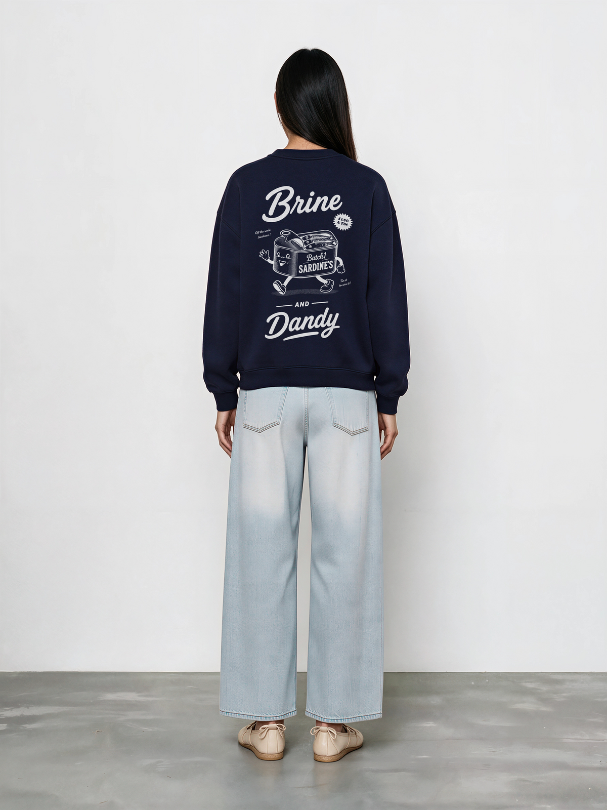 Brine and Dandy navy sweatshirt, back female model, showing the larger white Brine and Dandy sardine design on the back