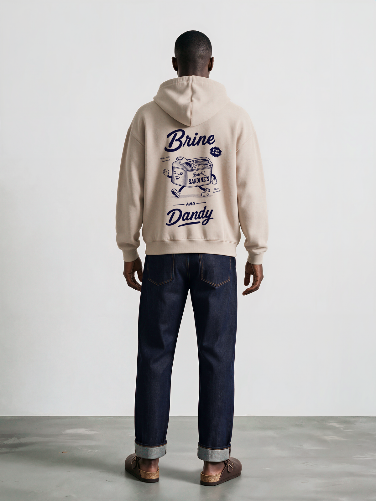 Brine and Dandy stone hoodie, back male model, showing the larger navy Brine and Dandy sardine design on the back