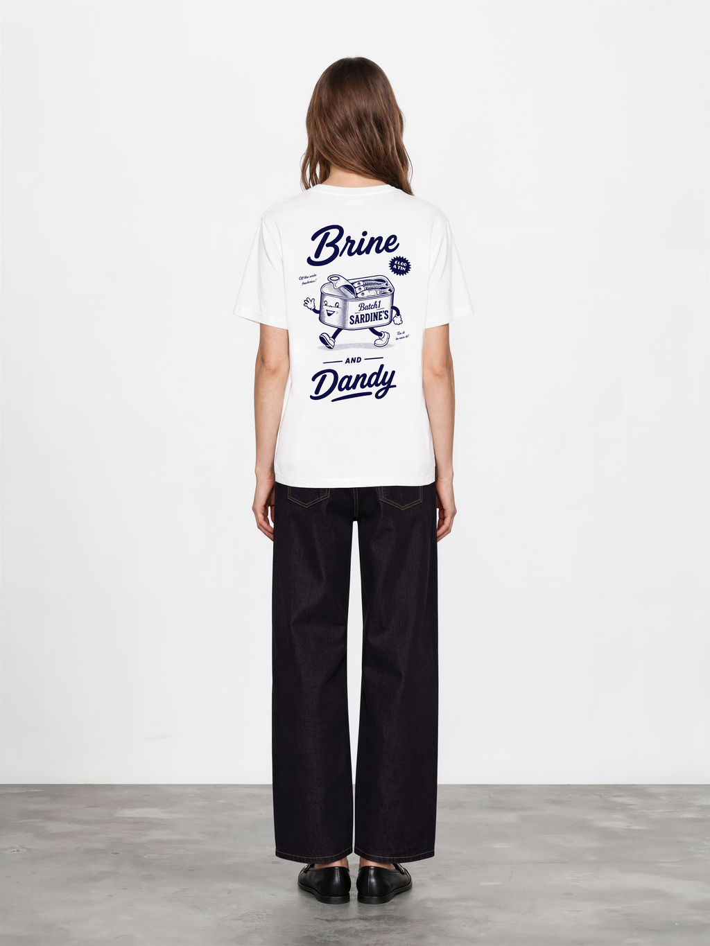 Brine and Dandy white T-shirt, back female model, showing the larger navy Brine and Dandy sardine design on the back