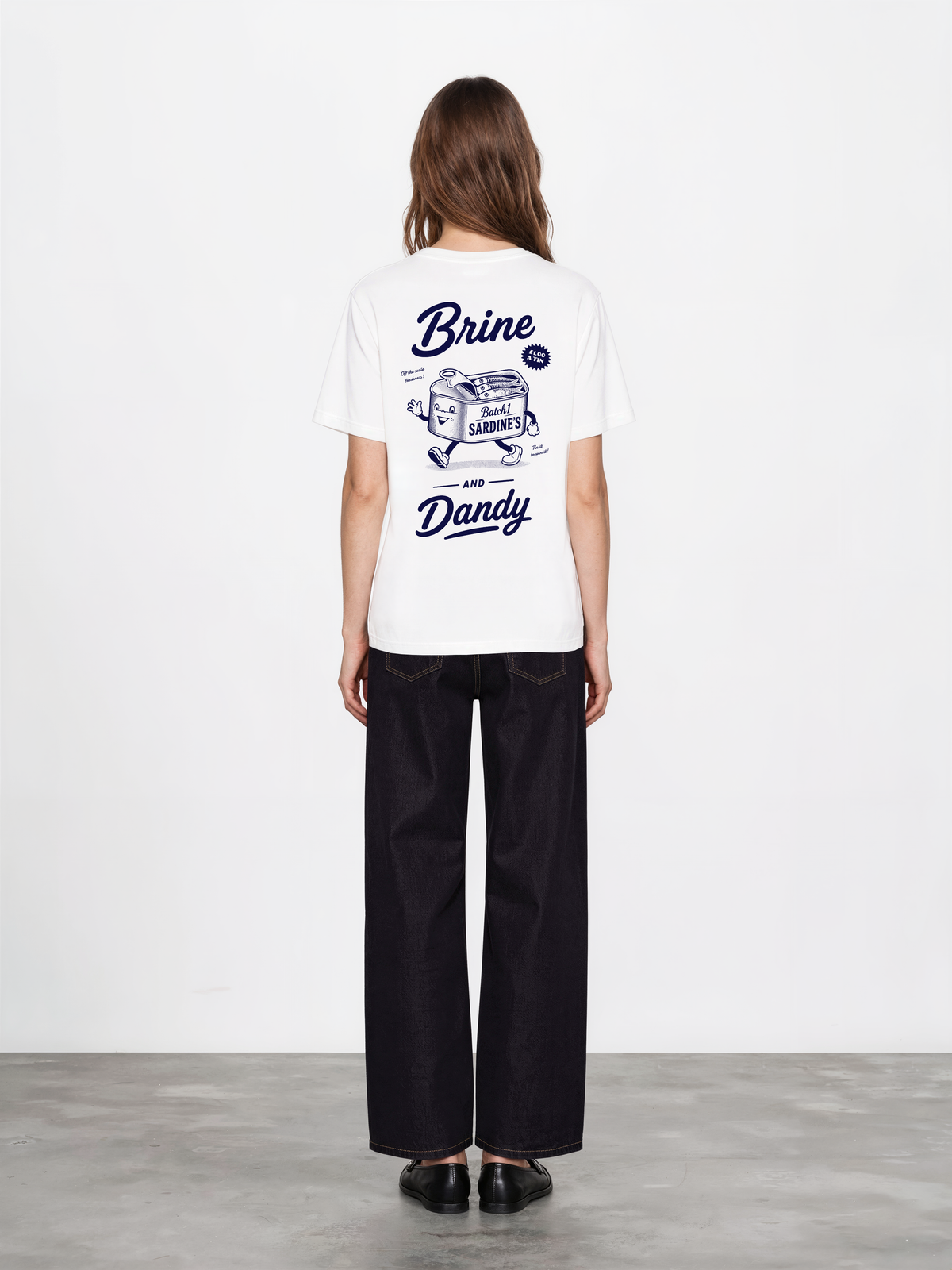 Brine and Dandy white T-shirt, back female model, showing the larger navy Brine and Dandy sardine design on the back
