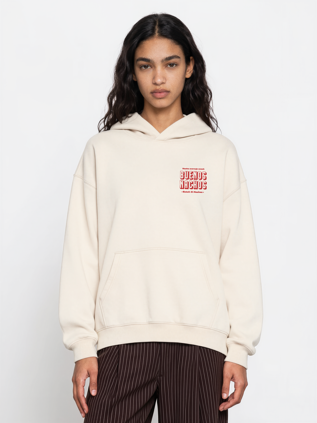 Female model wearing the Buenos Nachos ivory oversized hoodie, front view showing the red left-chest print.