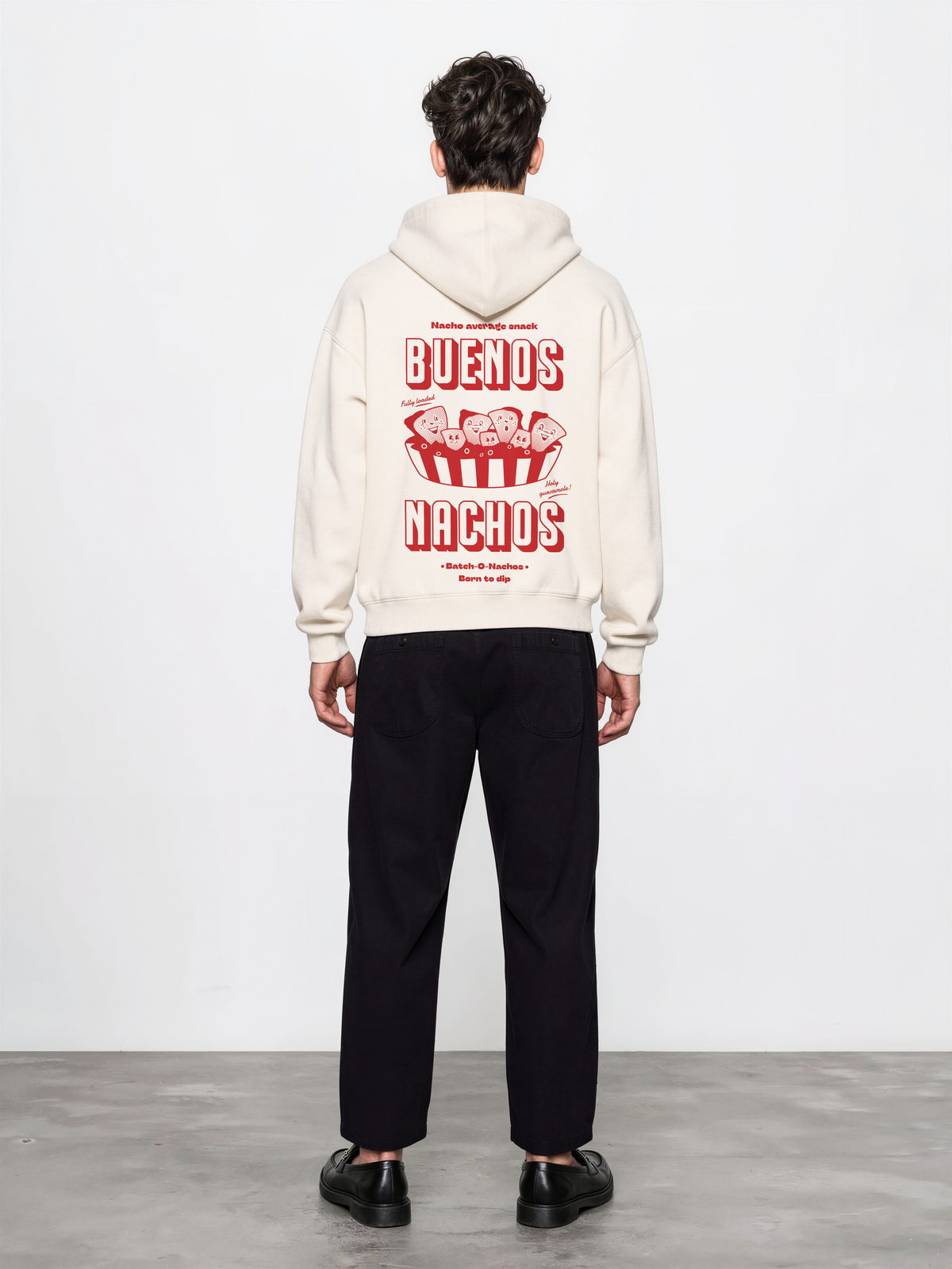 Male model wearing the Buenos Nachos ivory oversized hoodie, back view showing the red nacho illustration and lettering on the back.