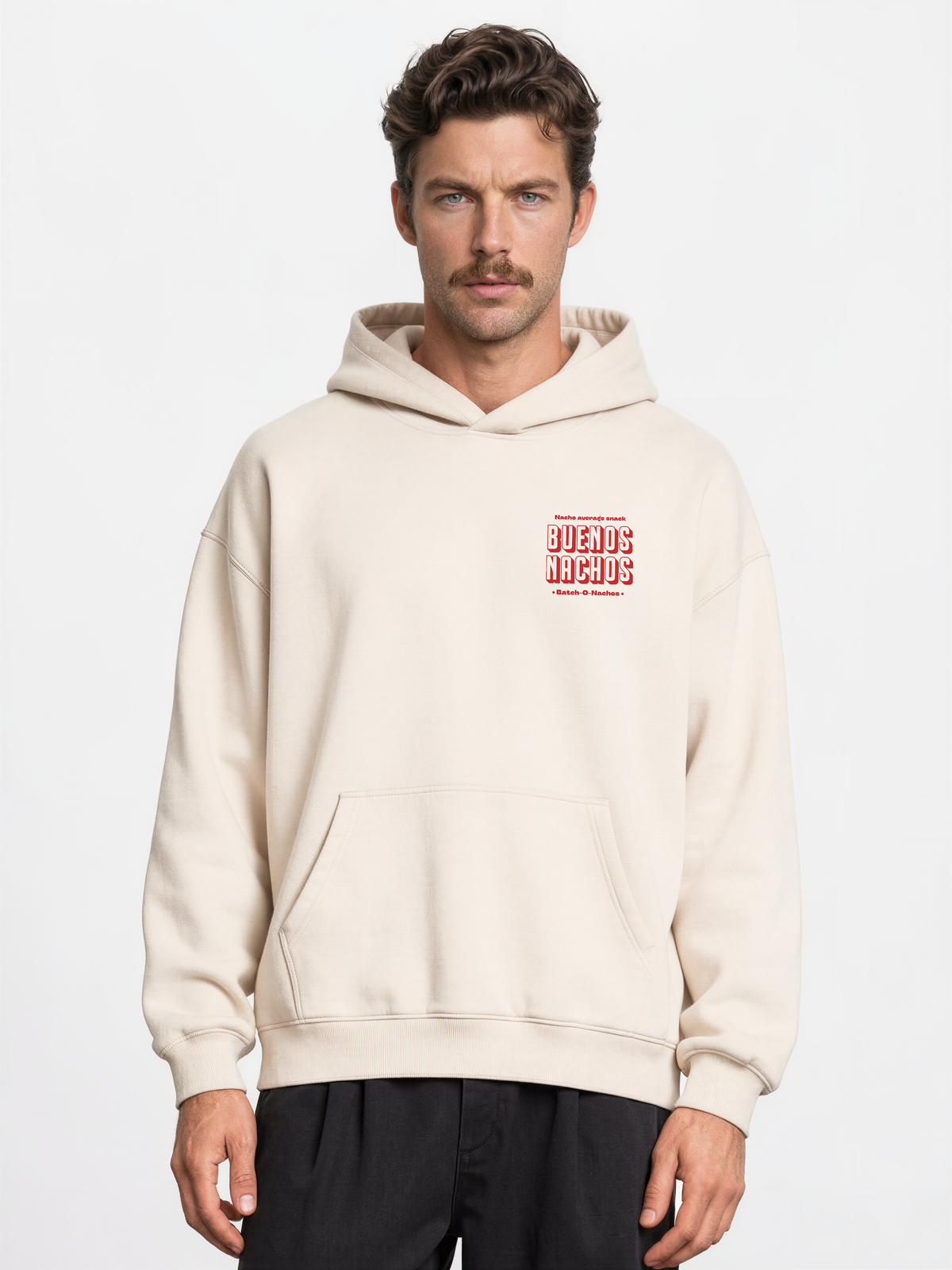Male model wearing the Buenos Nachos ivory oversized hoodie, front view showing the red left-chest print.