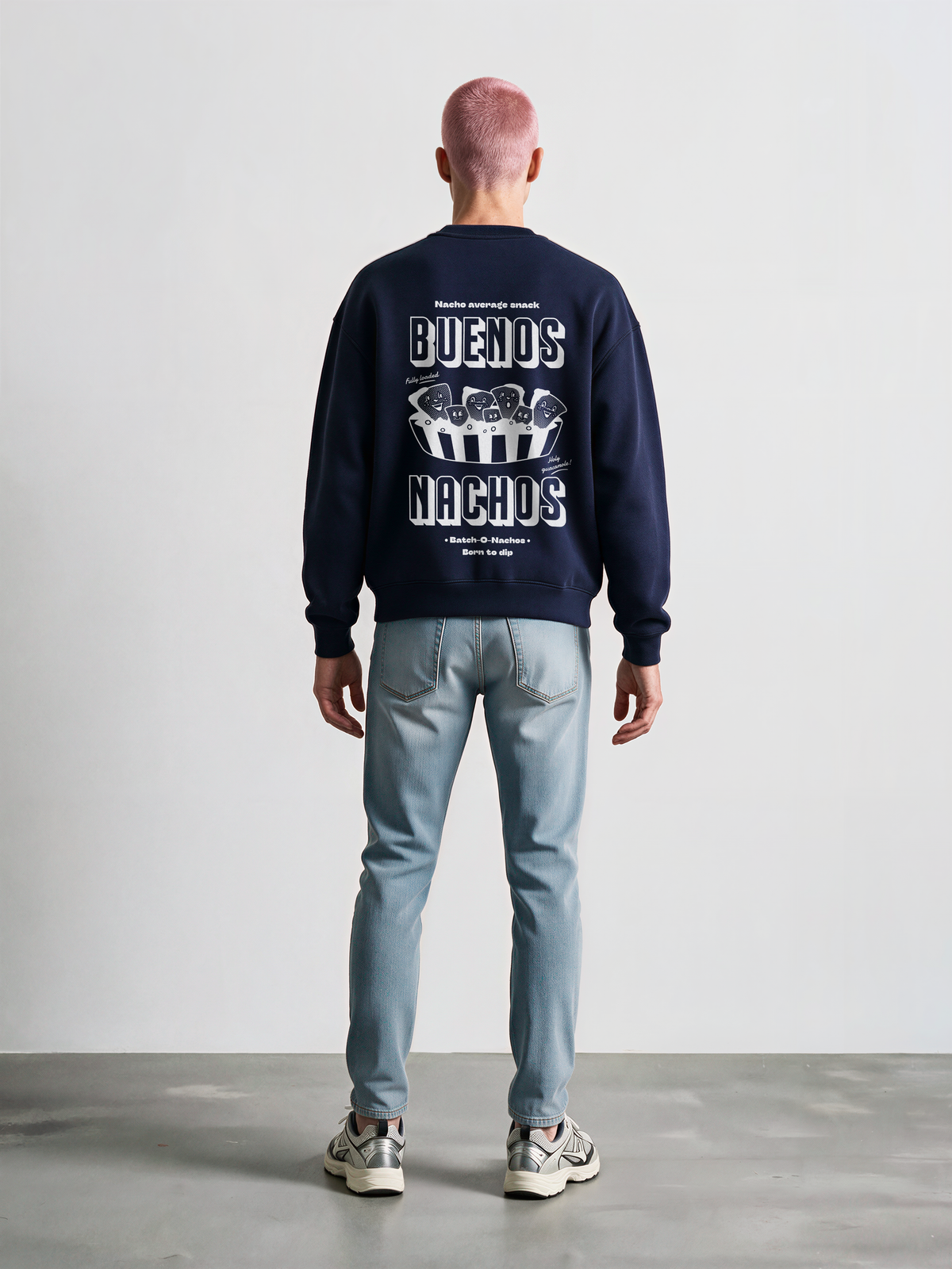 Male model wearing the Buenos Nachos navy oversized sweatshirt, back view showing the white nacho illustration and lettering on the back.