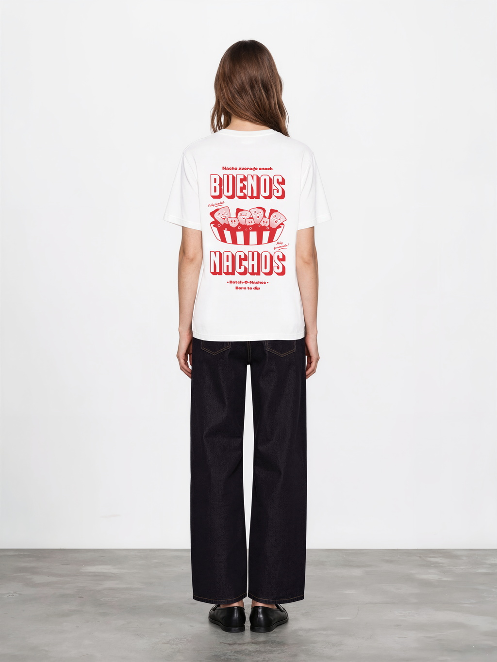 Female model wearing the Buenos Nachos white T-shirt, back view showing the red nacho illustration and lettering on the back.
