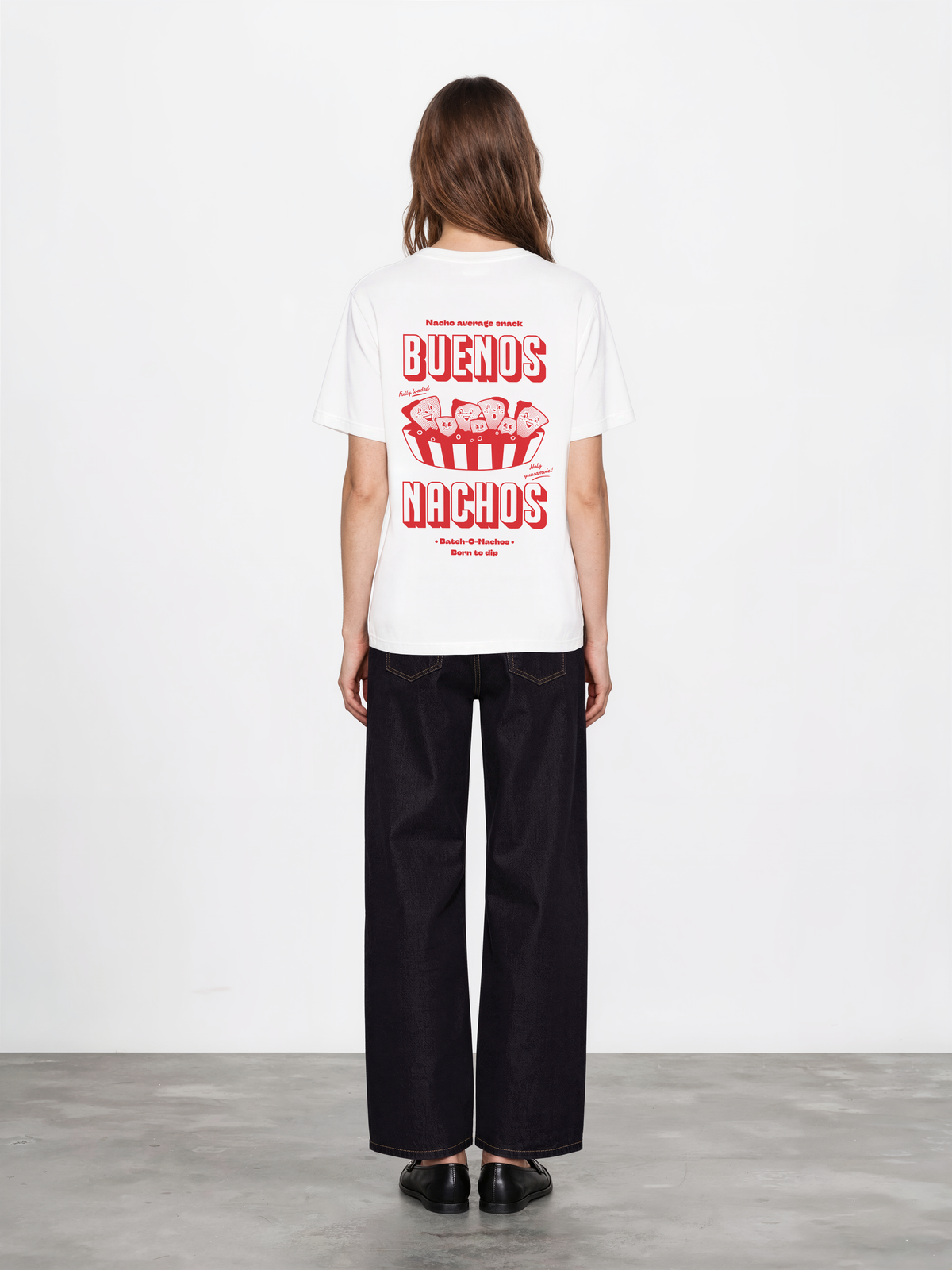 Female model wearing the Buenos Nachos white T-shirt, back view showing the red nacho illustration and lettering on the back.