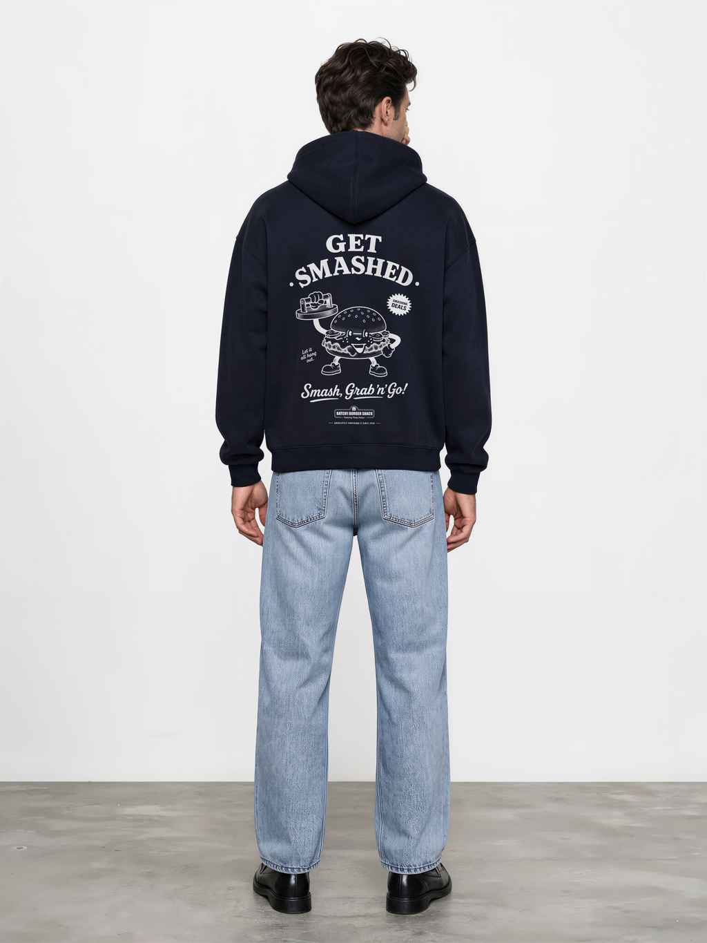 Male model wearing the Get Smashed navy oversized hoodie, back view showing the large white burger character and Get Smashed lettering beneath the hood.