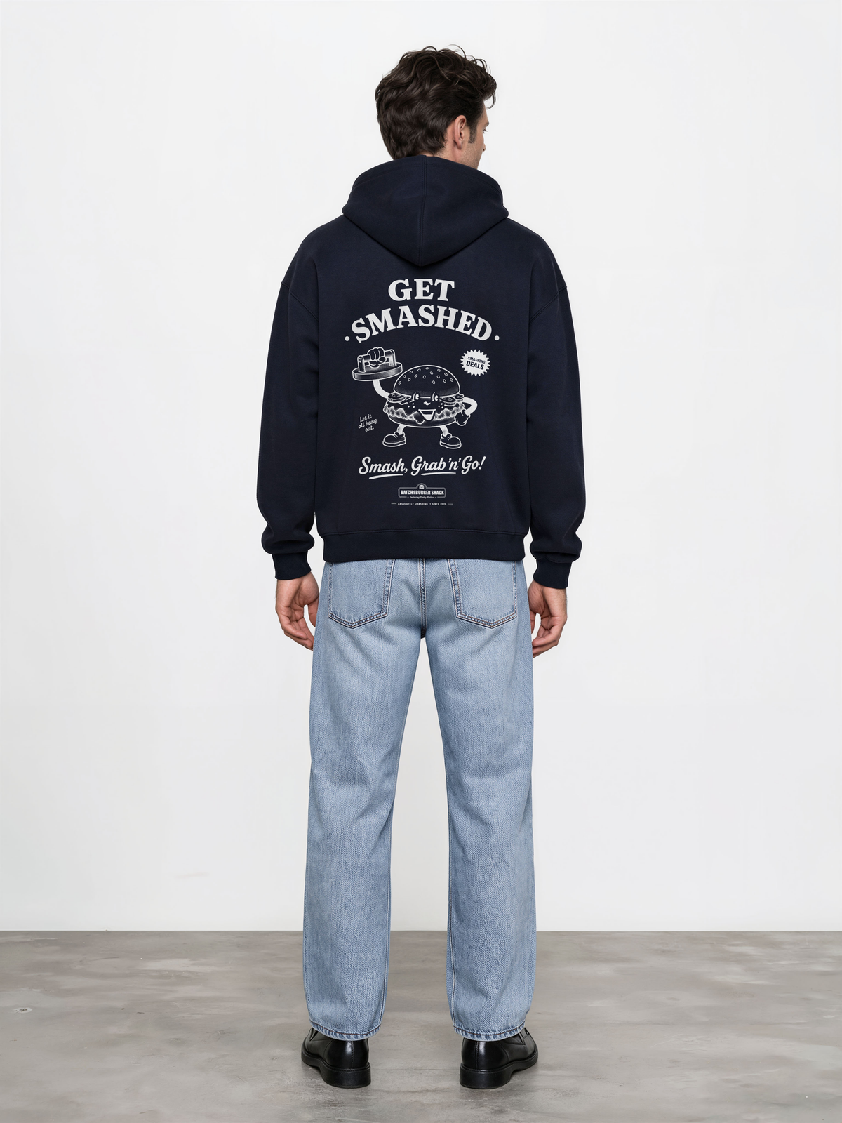 Male model wearing the Get Smashed navy oversized hoodie, back view showing the large white burger character and Get Smashed lettering beneath the hood.