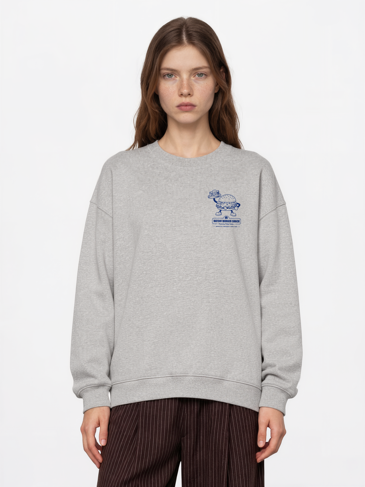 Female model wearing the Get Smashed ash oversized sweatshirt, front view showing the small blue burger graphic on the left chest.