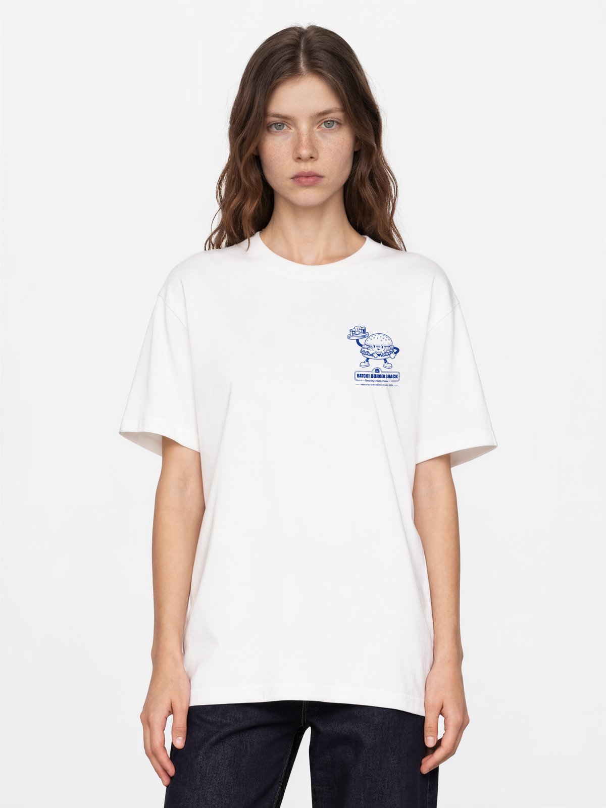 Female model wearing the Get Smashed white T-shirt, front view showing the small blue burger graphic on the left chest.