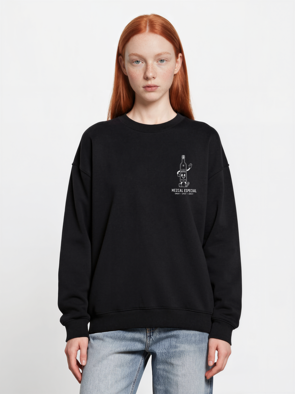 Female model wearing the black Holy Smokes oversized sweatshirt, showing the small white mezcal bottle screen print on the left chest