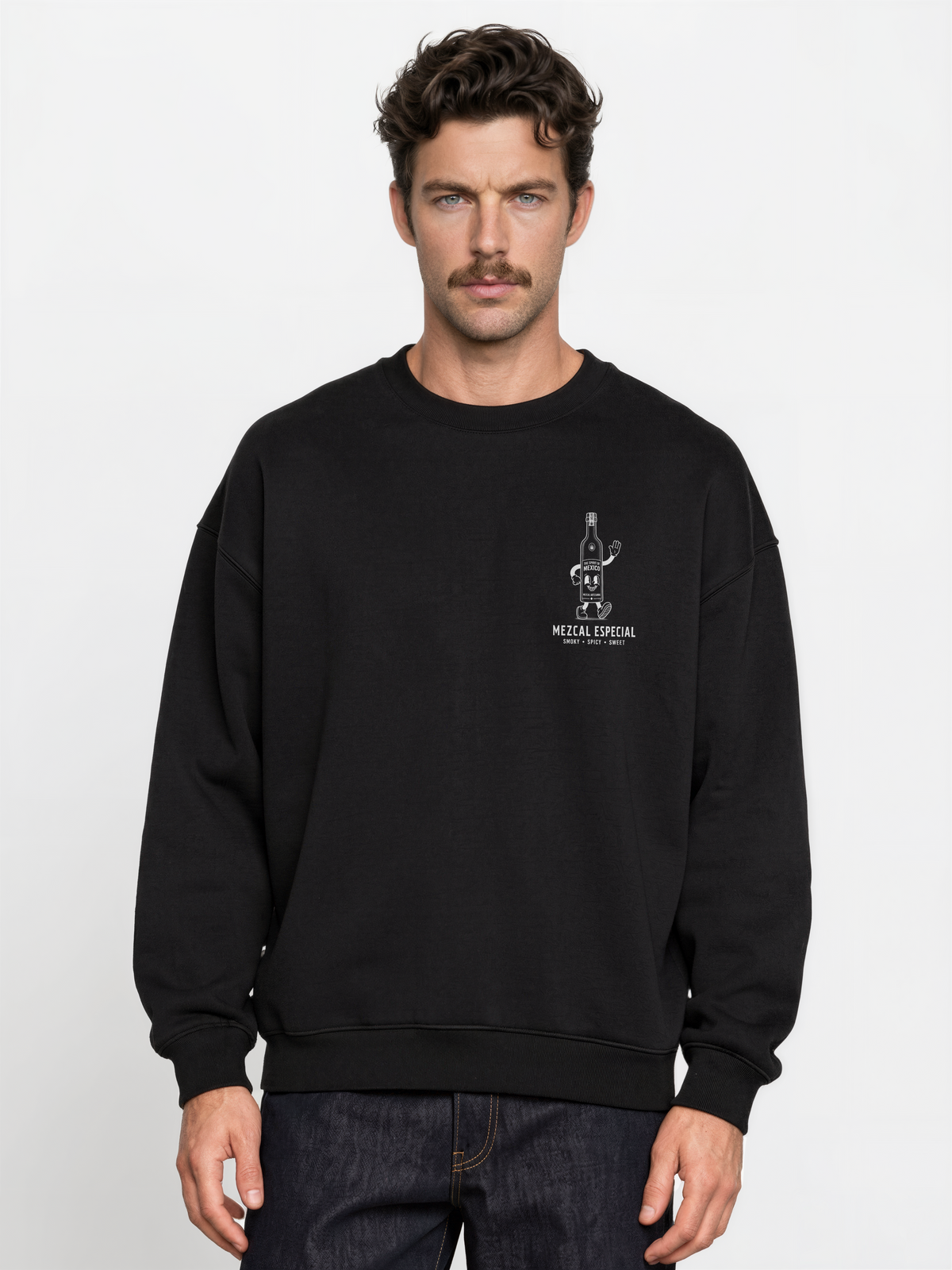 Male model wearing the black Holy Smokes oversized sweatshirt, showing the small white mezcal bottle screen print on the left chest