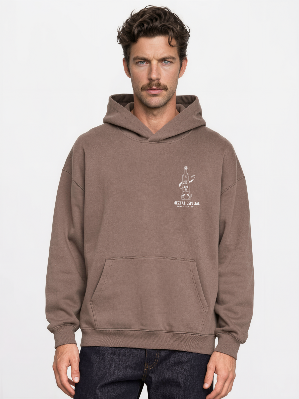 Male model wearing the mocha Holy Smokes oversized hoodie, showing the small white mezcal bottle screen print on the left chest