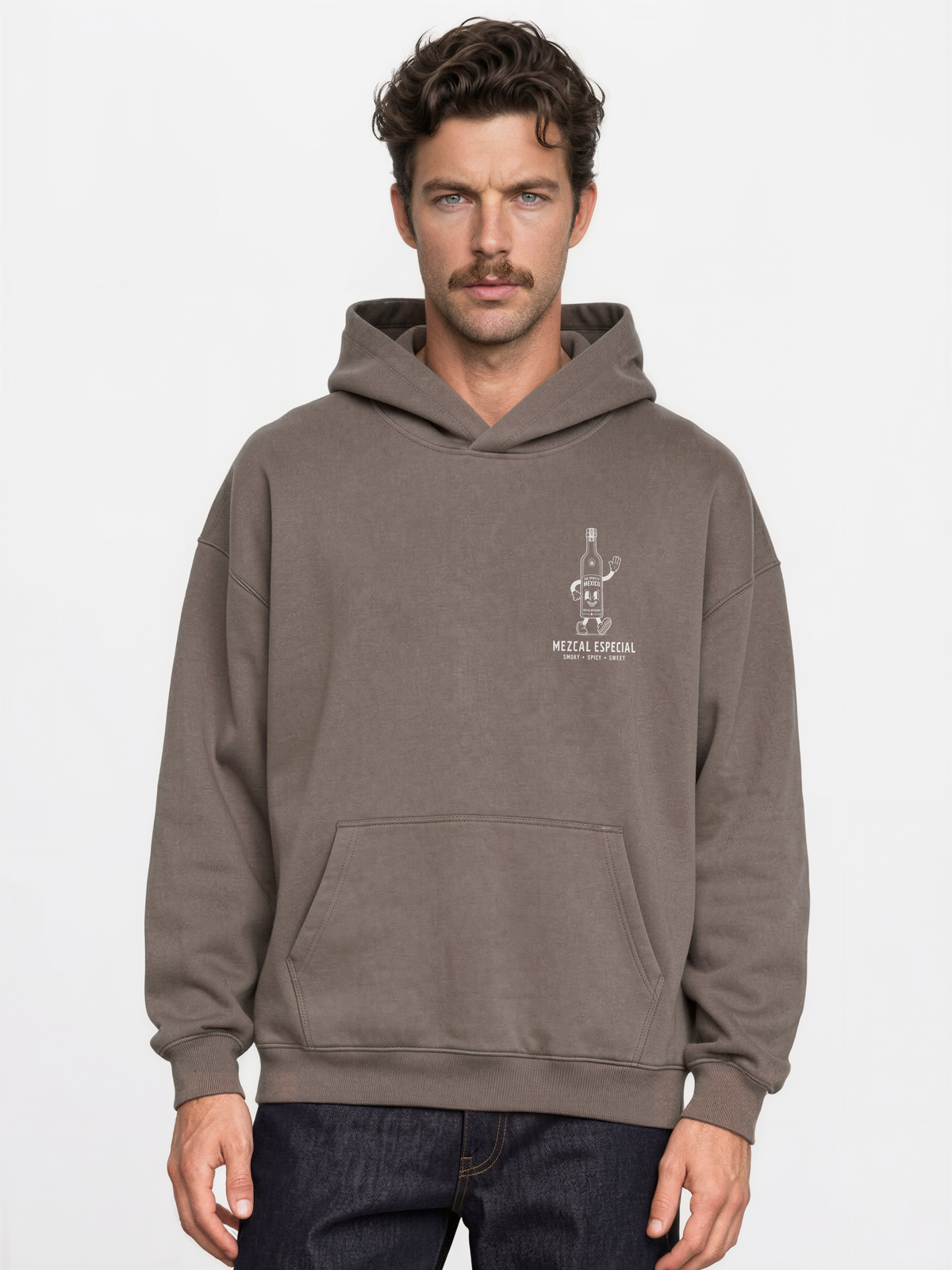 Male model wearing the taupe Holy Smokes oversized hoodie, showing the small white mezcal bottle screen print on the left chest