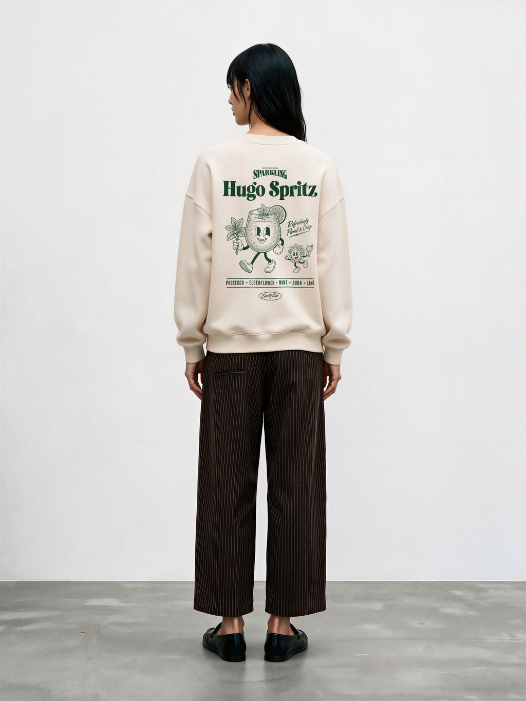 Female model wearing the Hugo Spritz Ivory oversized sweatshirt, showing the large green back print