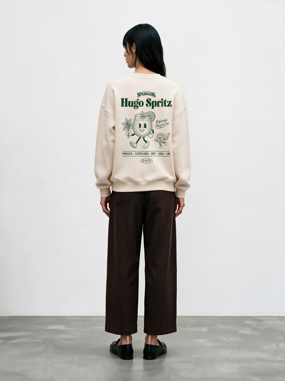Female model wearing the Hugo Spritz Ivory oversized sweatshirt, showing the large green back print
