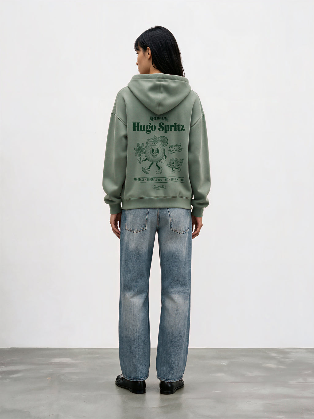 Female model wearing the Hugo Spritz Pine oversized hoodie, showing the large back print