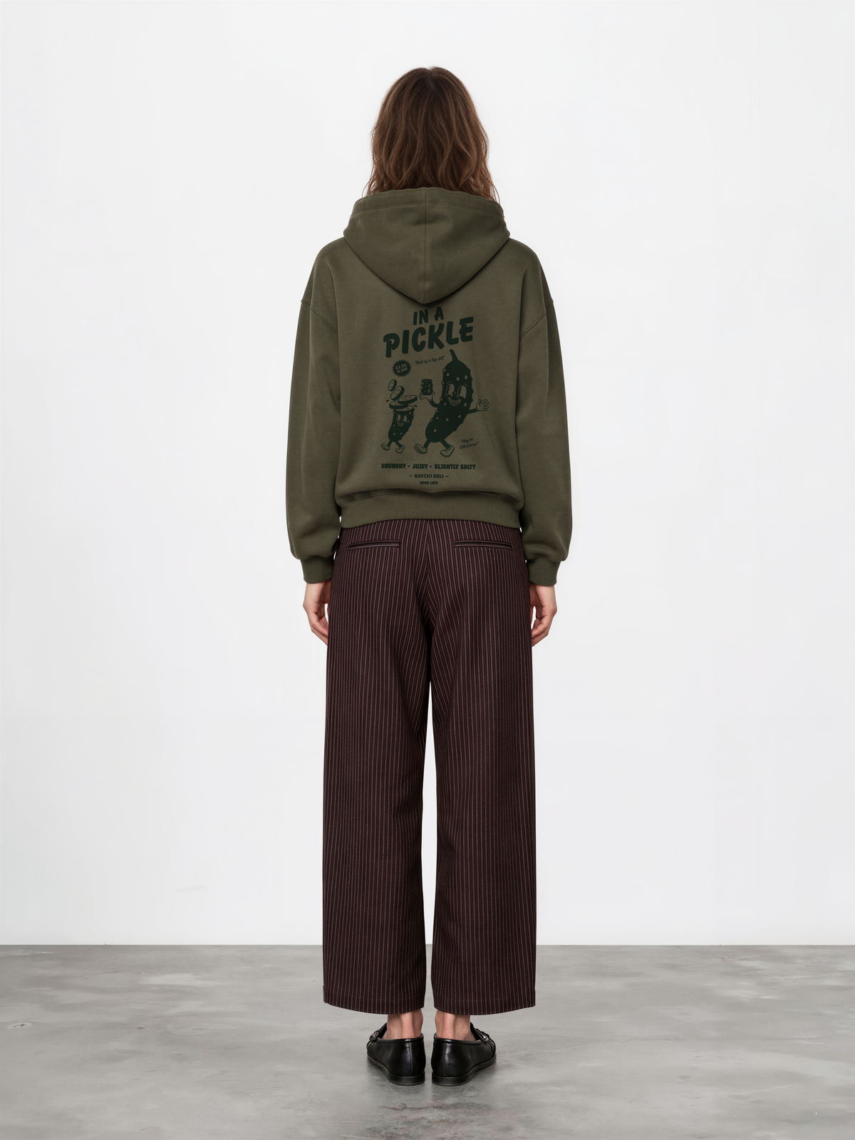 Female model wearing the Batch1 In a Pickle oversized olive hoodie, back view with dark green large pickle graphic.