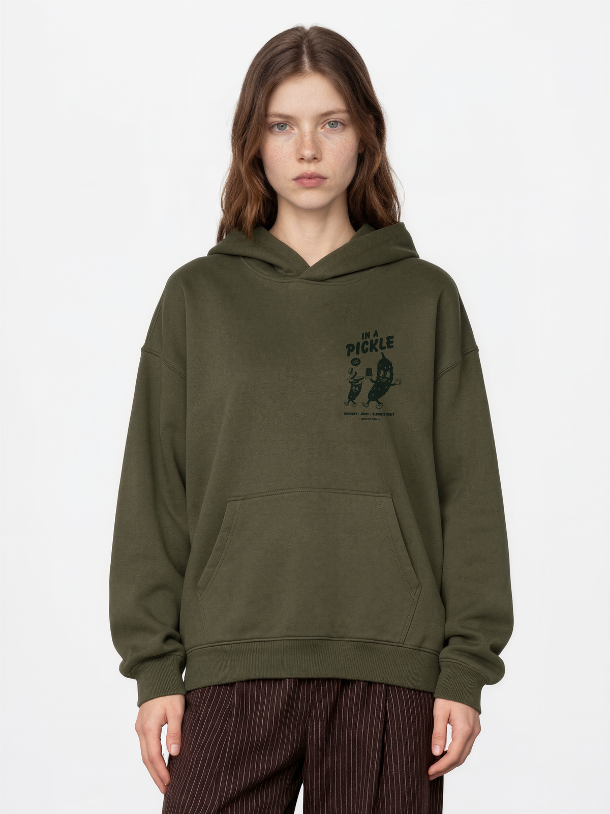 Female model wearing the Batch1 In a Pickle oversized olive hoodie, front view with dark green left-chest print.