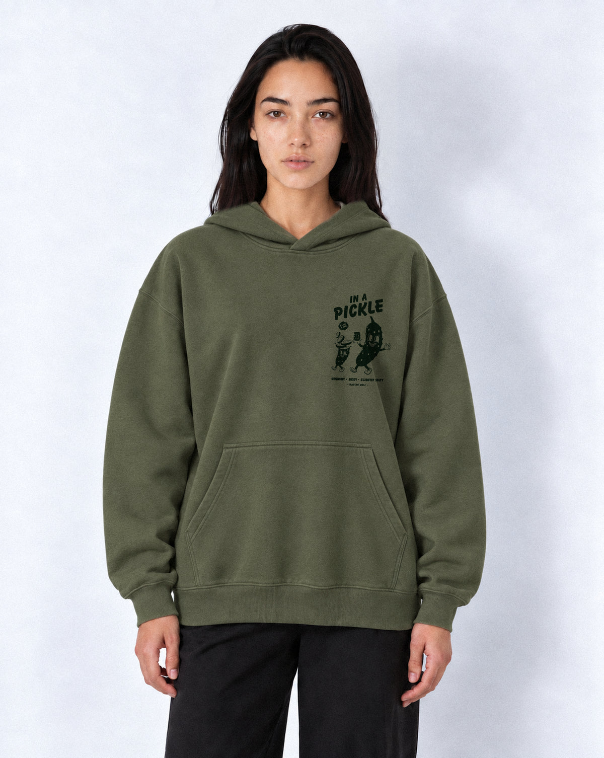 Female model wearing the Batch1 In a Pickle oversized Olive hoodie, front view with dark green left-chest print.