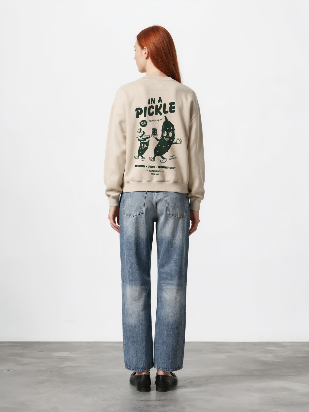 Female model wearing the Batch1 In a Pickle oversized Stone sweatshirt, back view with dark green large pickle graphic.