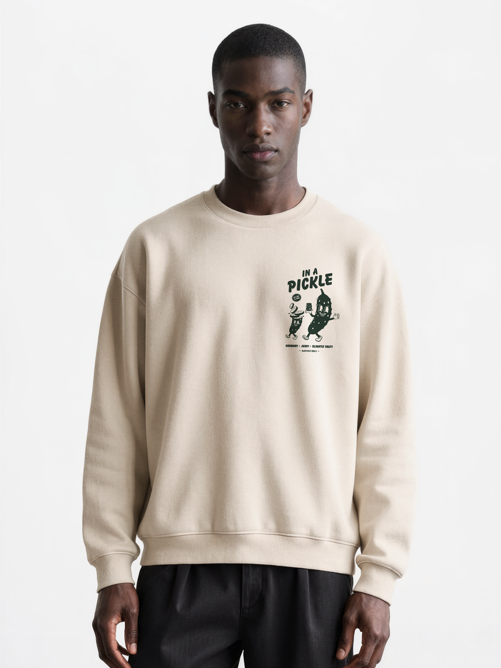Male model wearing the Batch1 In a Pickle oversized Stone sweatshirt, front view with dark green left-chest print.