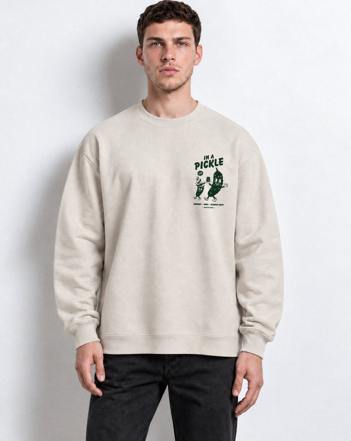 Male model wearing the In a Pickle oversized sweatshirt in Stone, front view with left chest dark green graphic