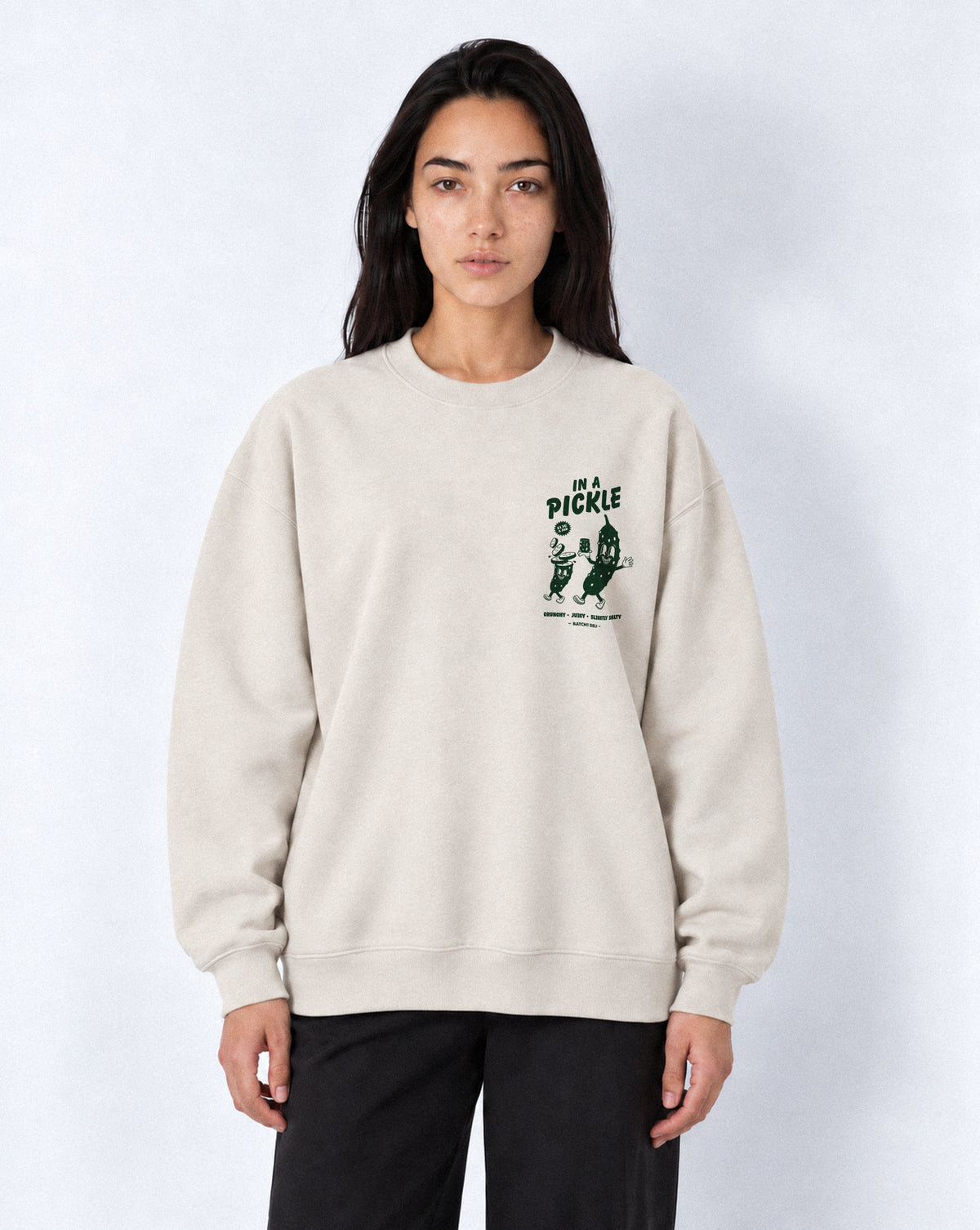Female model wearing the In a Pickle oversized sweatshirt in Stone, front view with left chest dark green graphic