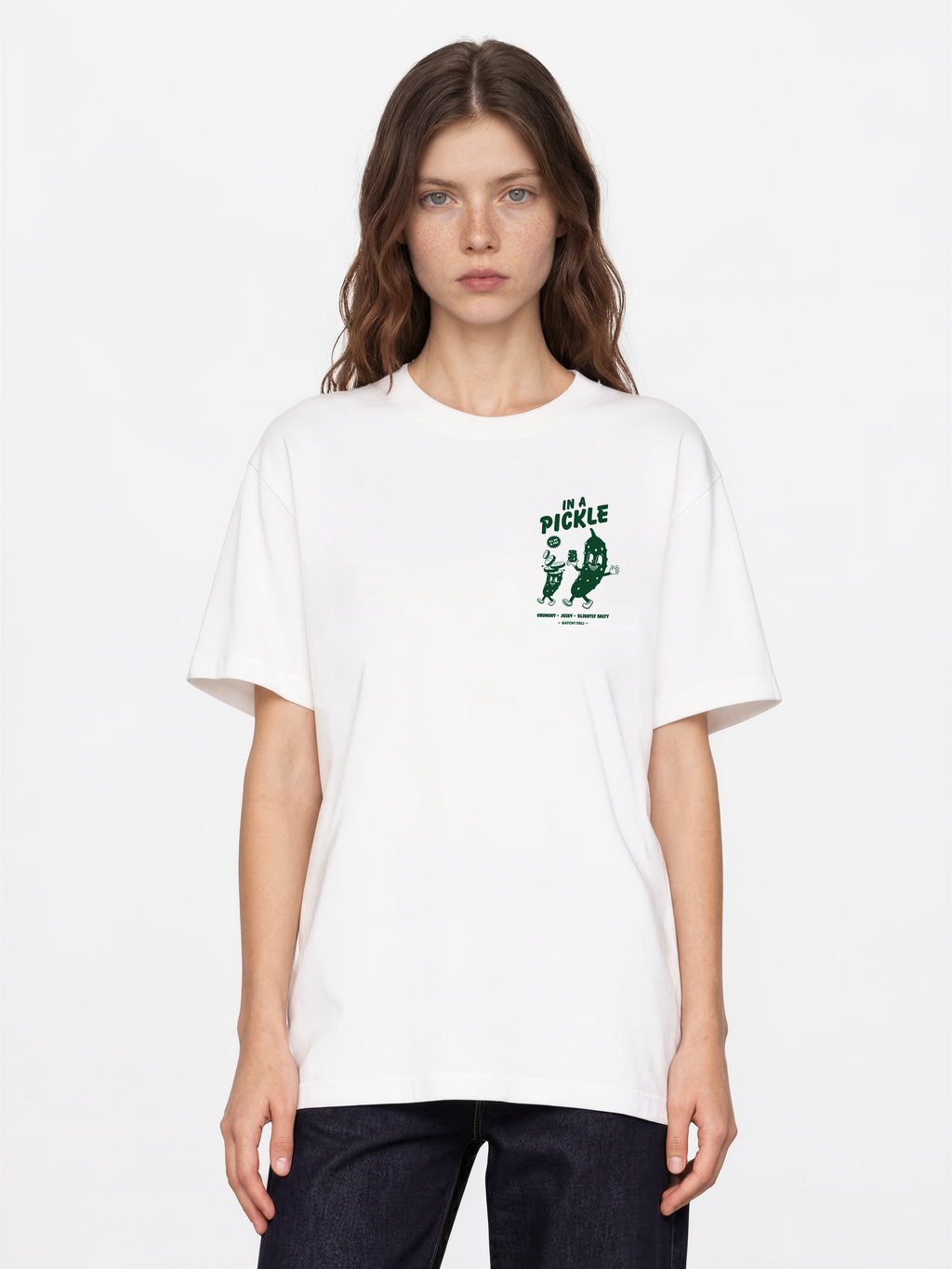 Female model wearing the Batch1 In a Pickle white T-shirt, front view with dark green left-chest print.