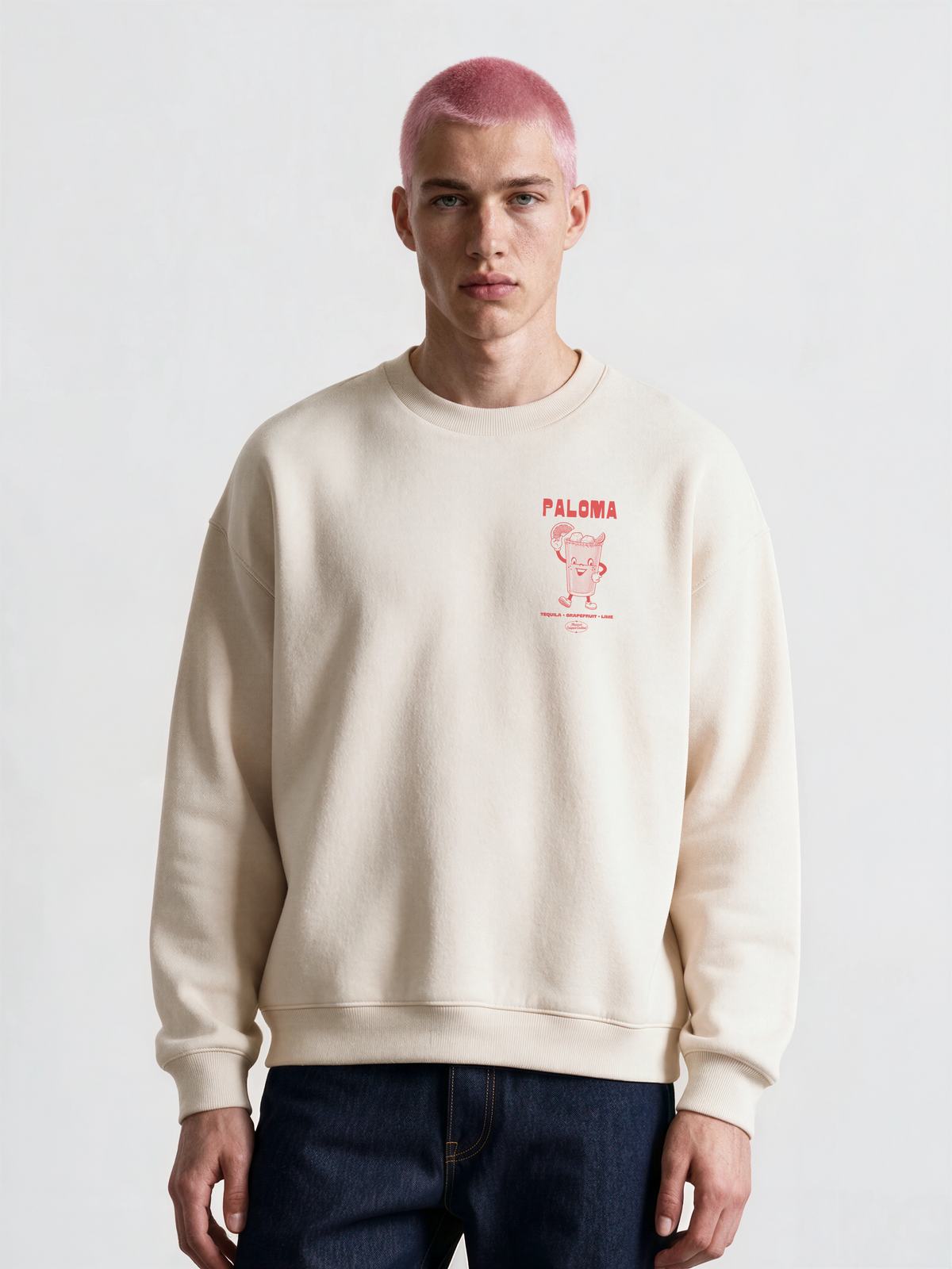 Male model wearing the Paloma ivory oversized sweatshirt, front view showing the coral cocktail graphic on the left chest.