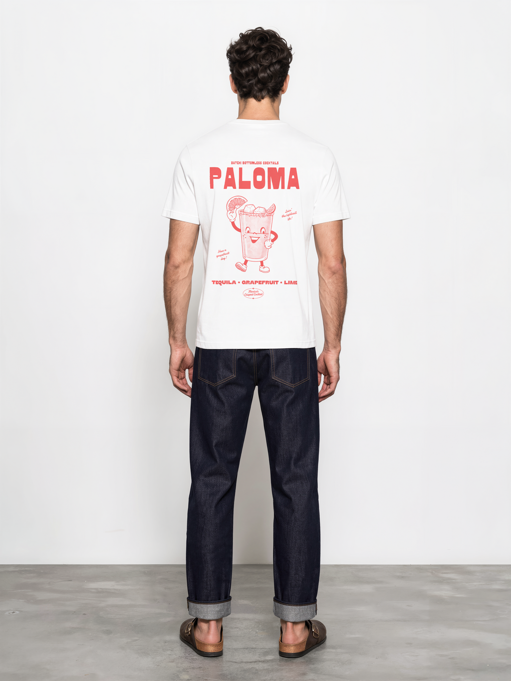 Male model wearing the Paloma white T-shirt, back view showing the large coral cocktail character graphic.