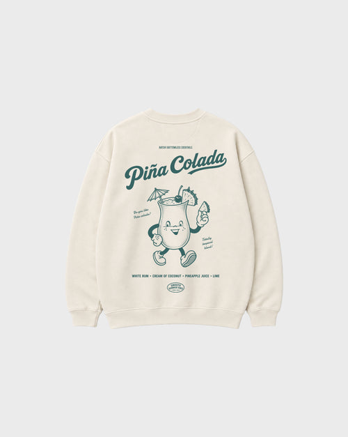 Back flat lay of the Piña Colada ivory oversized sweatshirt, showing the large teal tropical cocktail character and Piña Colada lettering on the back.