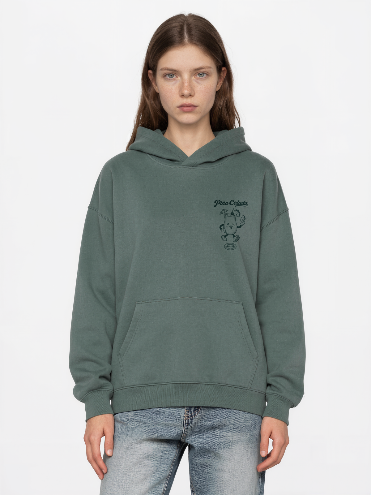 Female model wearing the Piña Colada pine oversized hoodie, showing the small teal Piña Colada cocktail print on the left chest.