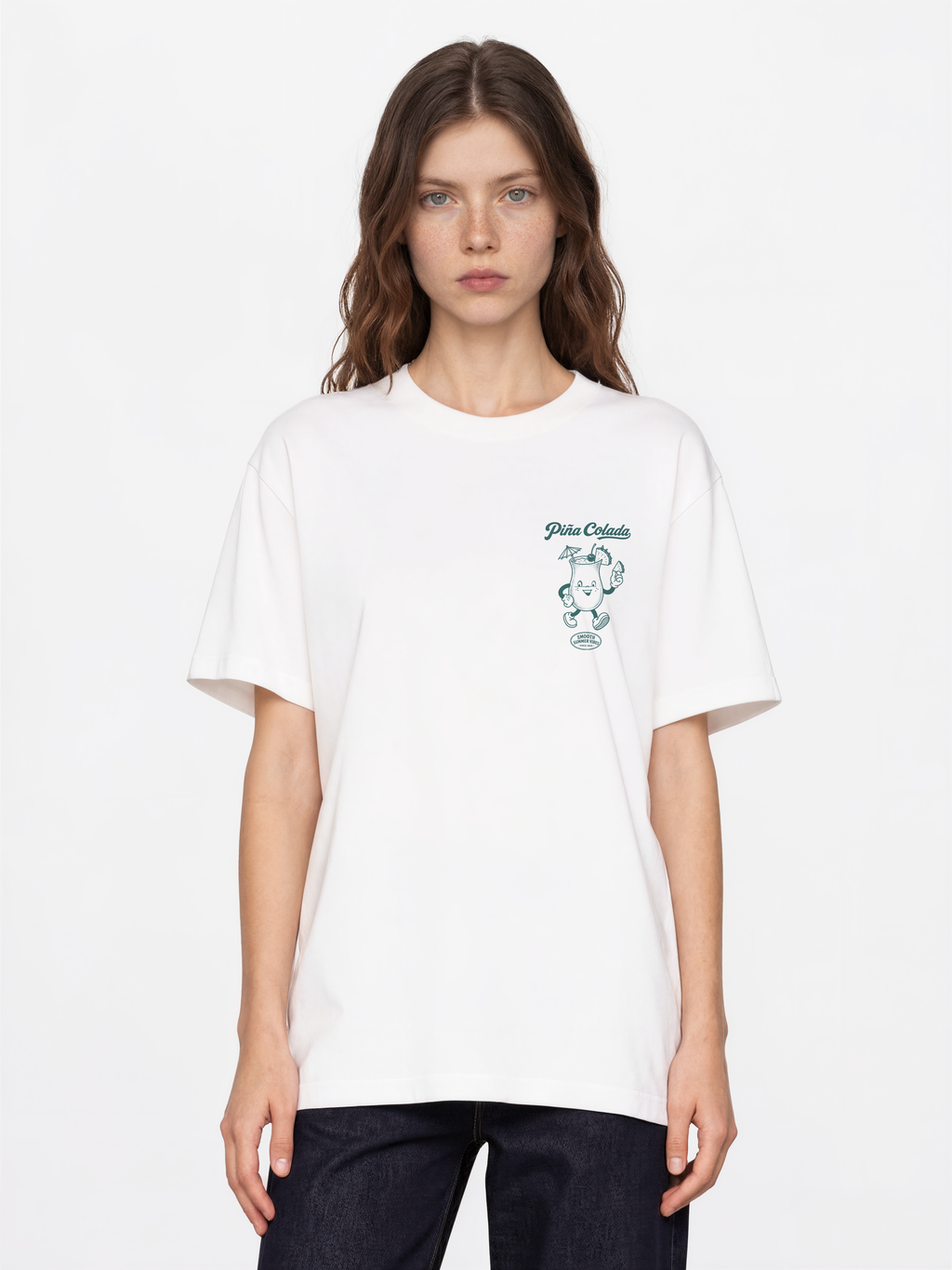 Female model wearing the Piña Colada white T-shirt, front view showing the teal left-chest cocktail print.
