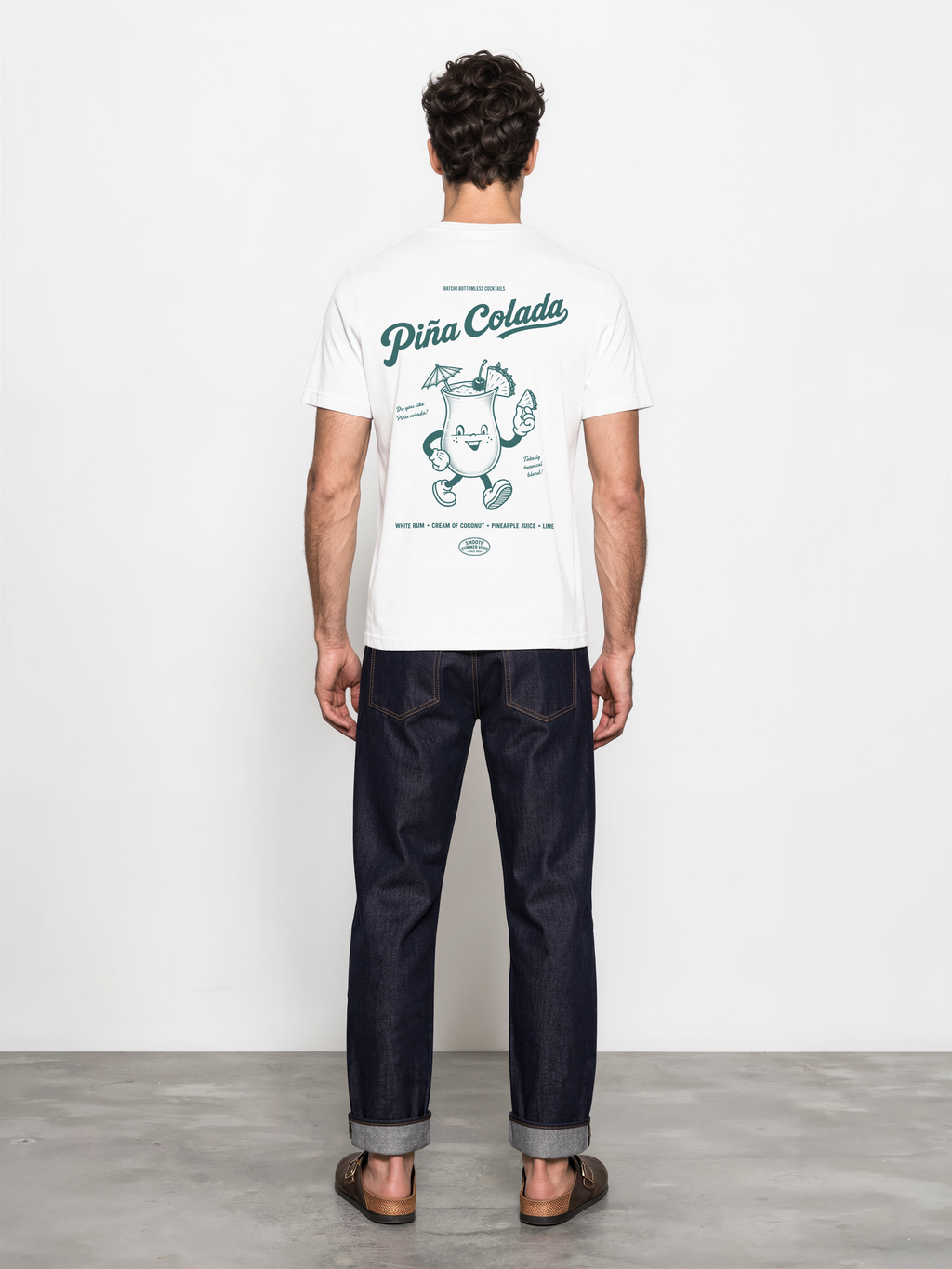 Male model wearing the Piña Colada white T-shirt, back view showing the large teal cocktail character graphic.